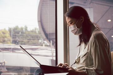 Asian woman with face mask working with notebook laptop in cafe. Concept for new normal and life in...