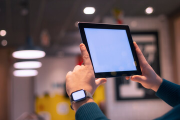 Businessman with smart watch and digital tablet with a white screen in his hands. A male freelancer works in a cafe.