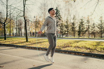 sports cardio warm-up before active fitness on the autumn street. athlete male Caucasian appearance engaged in training on the street portrait, jumping rope for a long time.