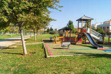 Playground and play area for children in the Río Guadaira park in Seville (Andalusia, Spain). Wooden house for children with slides surrounded by grass. Sunny day to enjoy the outdoors.
