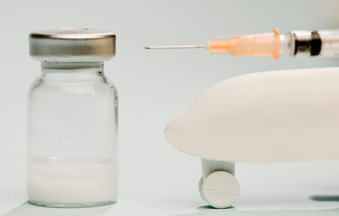 Vaccine in glass vial, with white plane,with syringe, blue background.
