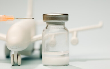 Vaccine in glass vial, with syringe, white plane, blue background.