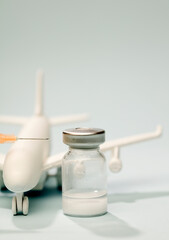 Vaccine in glass vial, with syringe, white plane, blue background.