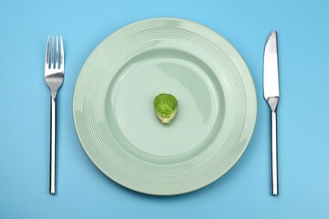 bruxelle sprouts on a plate with knife and fork on blue background 