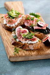 Variety of mini sandwiches with cream cheese, vegetables and salami.