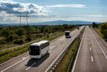 Three White Modern comfortable tourist buses in line driving through highway at bright sunny day....