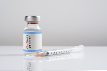 Covid-19 Written vaccine bottle with a syringe on a white background