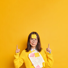 Funny crazy female student crosses eyes makes grimace tired of working long prepares diploma paper...