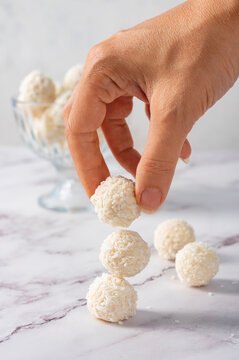 Coconut balls, ehite chocolate rafaello candies. Vegetarian round tasty dessert, hand holding a ball