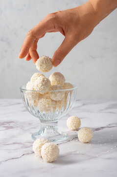 Coconut balls, ehite chocolate rafaello candies. Vegetarian round tasty dessert, hand holding a ball