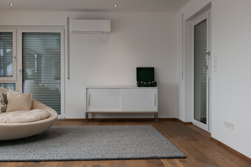 Wohnzimmer mit Plattenspieler am Regal, rundem Sofa und Holzfußboden. 
