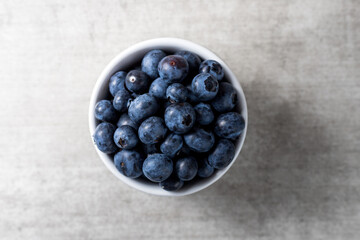 Lot of fresh delicious blueberries on a white pot over a wooden table