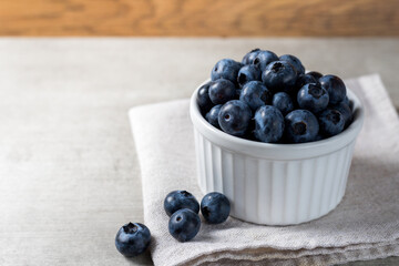 Lot of fresh delicious blueberries on a white pot over a wooden table
