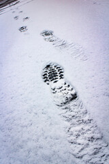 Shoe prints in the snow on black asphalt