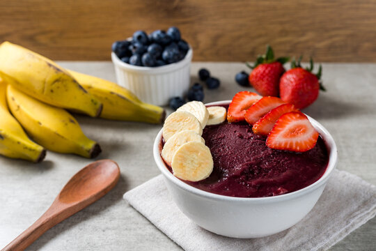 Brazilian frozen açai berry ice cream bowl with strawberries and bananas. with fruits on wooden background. Summer menu front view