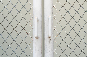 White chain link fence and rusty metal door against electrical control cabinet background.