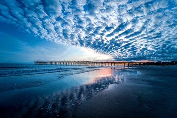 An ocean pier with dramatic clouds over the sea after sunset.