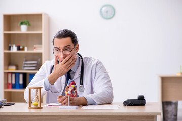 Young male doctor cardiologist in time management concept