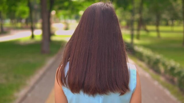 back view brunette with shine long hair walking on the street in summer season slow motion