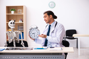 Young male doctor and skeleton patient in time management concep