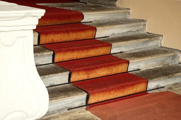 Red carpet over concrete stairs and part of a white stone balustrade