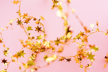 Blurred Golden star sprinkles on pink. Festive holiday background. Celebration concept. Top view, flat lay. Horizontal