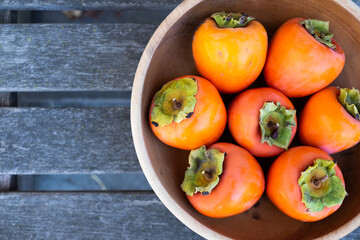 Persimmons in a Wooden Bowl on a Wooden Bench