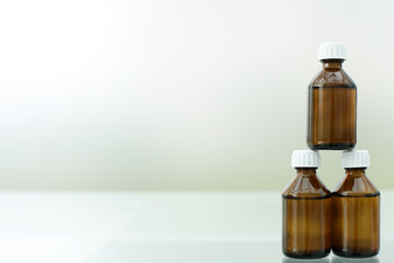 Three medicine bottles stand on a glass table