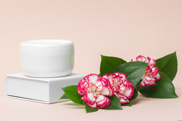 Beauty industry concept . White cosmetic cream jar top with flowers. Side view.  Feminine hygienic skincare product on light pink background .Сlose-up.