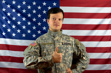American army soldier on the background of the American flag. Portrait of a US Soldier showing a class gesture. The concept of patriotism