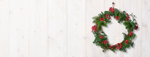 白い木製の壁に吊るされたクリスマスリース