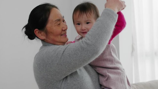 4k slow motion close up of senior asian woman holding her granddaughter dancing at home lovely kid playing with her grandmother indoor happy family lifestyles with kid