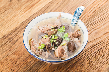 A bowl of mushroom lao duck soup on a cutting board