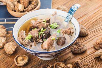 A bowl of mushroom lao duck soup on a cutting board