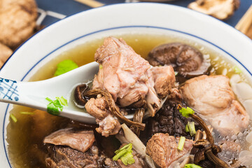 A bowl of mushroom lao duck soup on a cutting board