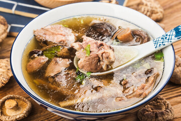 A bowl of mushroom lao duck soup on a cutting board