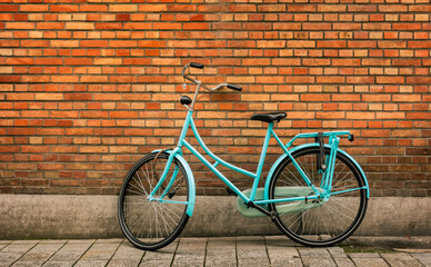 Fototapeta na wymiar Blue vintage bicycle standing in front of an orange brick wall in the city of Bruges.