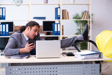 Young male employee looking after newborn at workplace
