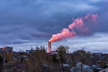 Smoke from an industrial chimney, illuminated by the setting sun
