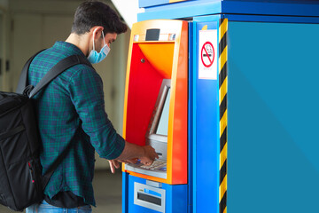 Caucasian man doing a financial transaction at a cash machine.