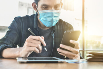 Asian man in face mask business people using mobile phone working online, Man Speculative stock...