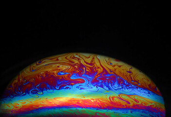 Macro picture of half soap bubble on black ground look like abstract psychedelic color planet in space