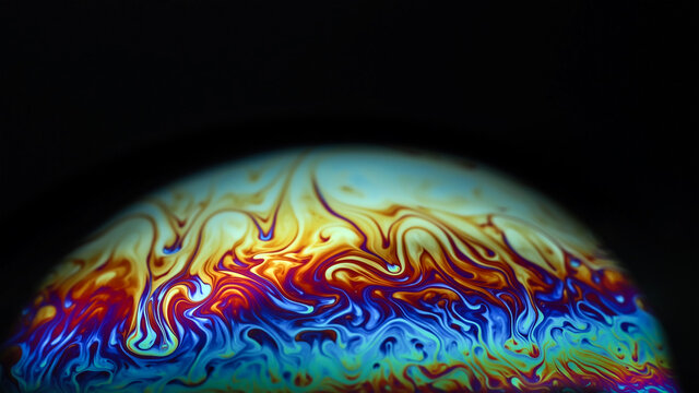 Macro picture of half soap bubble on black ground look like abstract psychedelic color planet in space