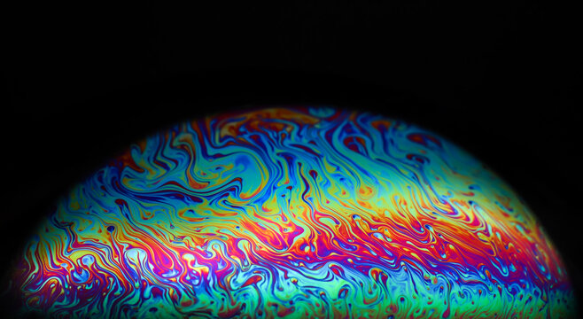 Macro picture of half soap bubble on black ground look like abstract psychedelic color planet in space
