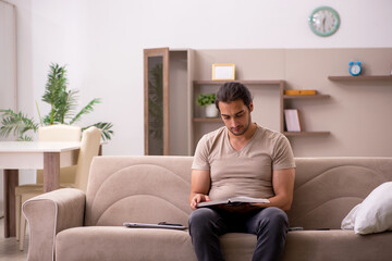 Young male student reading book at home