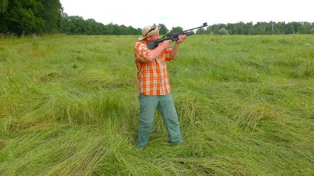 Hunter at cap and sunglasses aiming a gun