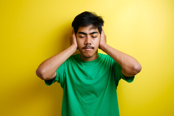 Fototapeta na wymiar Asian young man in green t-shirt close his ears with both hands