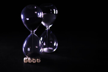 Sand running through the bulbs of an hourglass measuring the passing time in a countdown to a...
