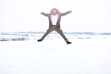 Fototapeta premium Outdoor portrait of handsome man in coat and scurf. Bearded man in the winter woods.