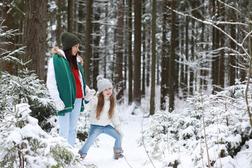 Young family for a walk. Mom and daughter are walking in a winter park.